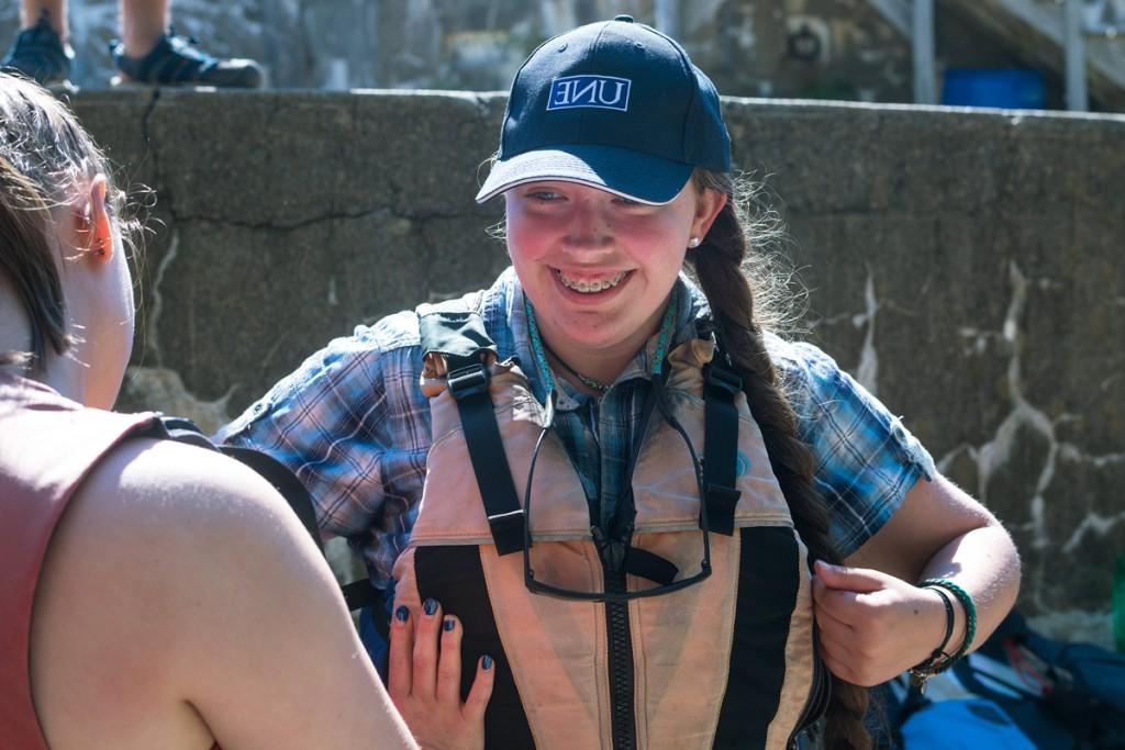 A student smiles as they put a life vest on